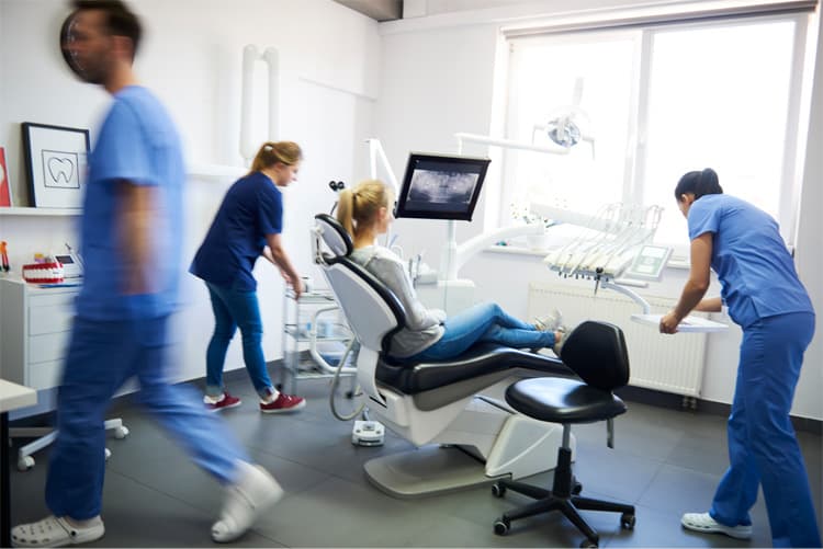 Dental staff hurry about to help patient